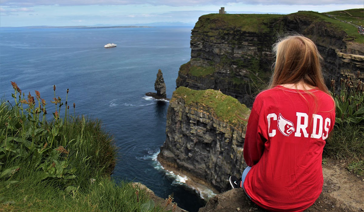Student sitting on the edge of the Cliffs of Moher